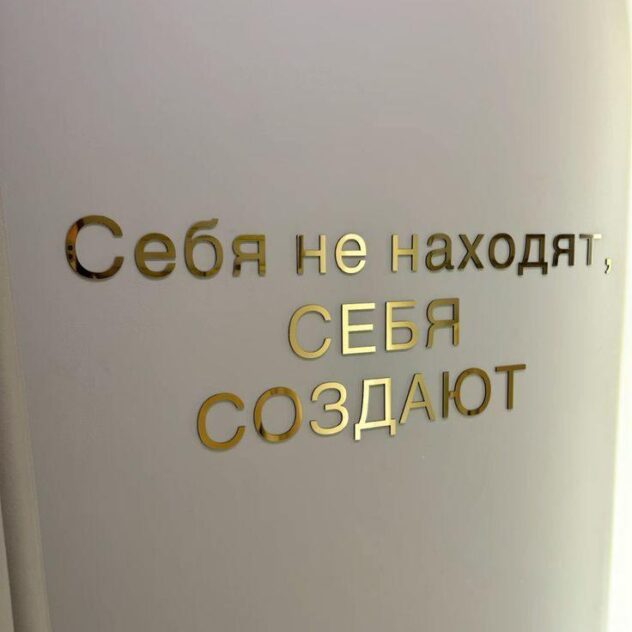 Золотые зеркальные плоские буквы-слоган на светлой стене