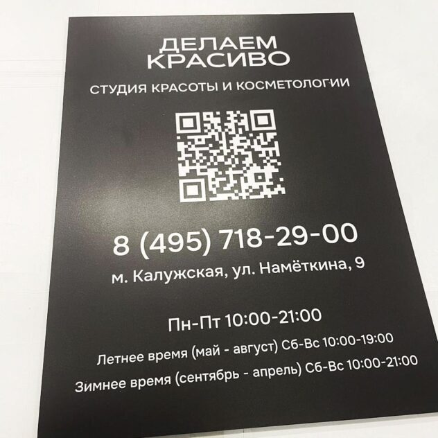 Чёрная табличка с режимом работы и QR-кодом студии