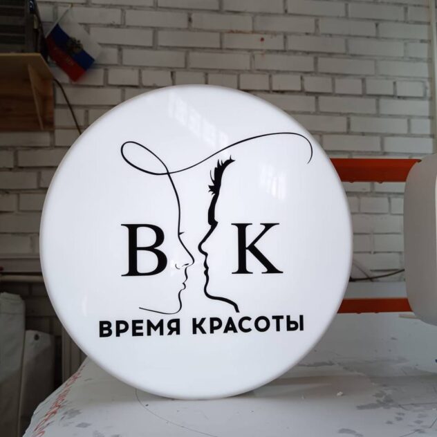Круглый световой короб с логотипом салона на столе